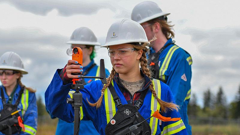 Lakeland College student measures wind speed during a proscribed fire lab.